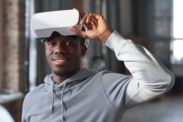 Ritratto di giovane africano con occhiali per realtà virtuale sulla testa che sorride alla telecamera