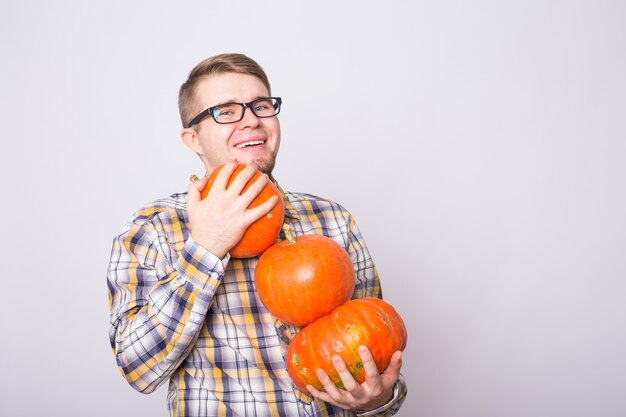 Ritratto di giovane agricoltore che tiene le zucche su uno studio leggero del fondo