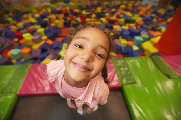 Ritratto di giovane bambina sorridente nella parte anteriore durante la riproduzione nel centro del trampolino