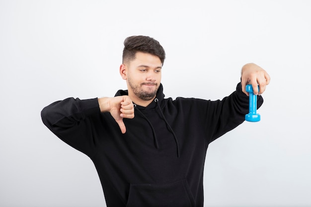 Ritratto di giovane bel ragazzo in felpa con cappuccio nera che tiene un manubrio leggero