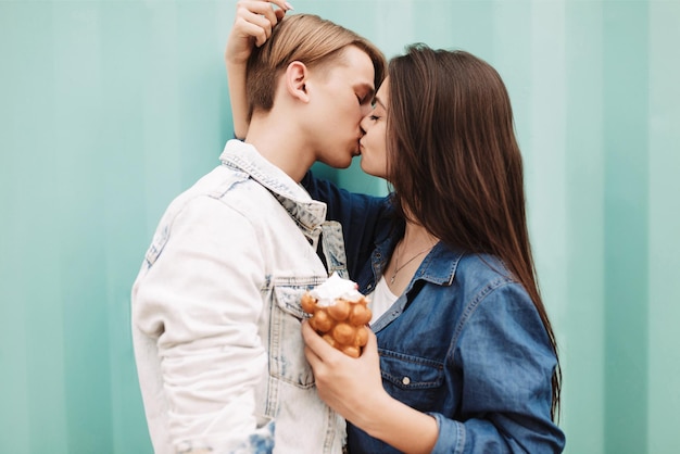 Ritratto di giovane bella coppia che si abbraccia e si bacia mentre in piedi su sfondo blu