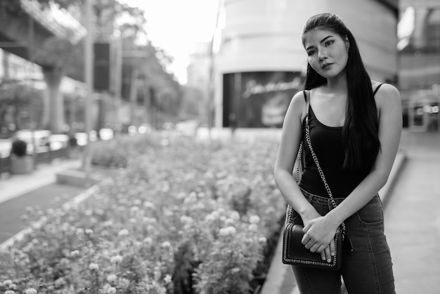 Ritratto di giovane bella donna asiatica che esplora la città in bianco e nero