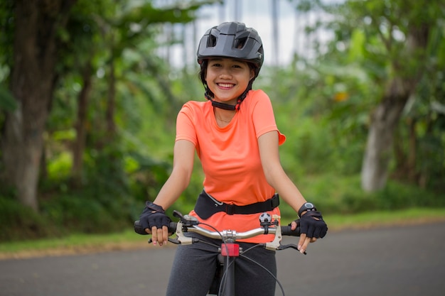 Ritratto di giovane bella donna asiatica che guida una bicicletta