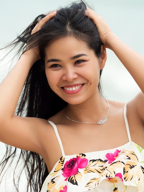Ritratto di giovane bella donna asiatica che sorride e che cammina fuori. Ragazza che tocca i suoi capelli. Concetto di ora legale, relax o vacanze
