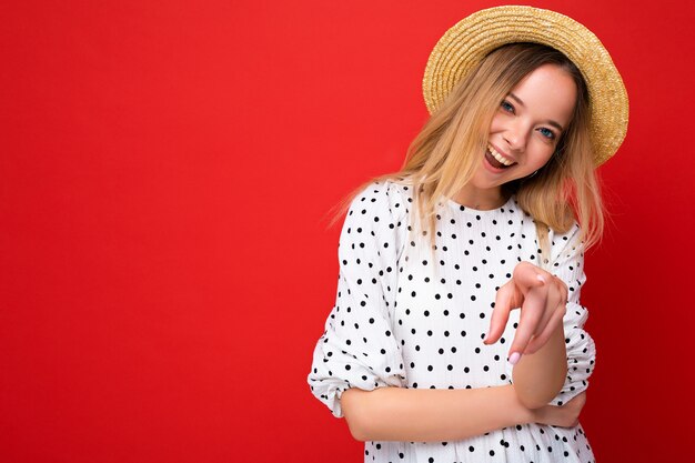 Ritratto di giovane bella donna bionda hipster sorridente in abito estivo alla moda e cappello di paglia sexy