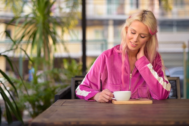 Ritratto di giovane bella donna bionda rilassante presso la caffetteria