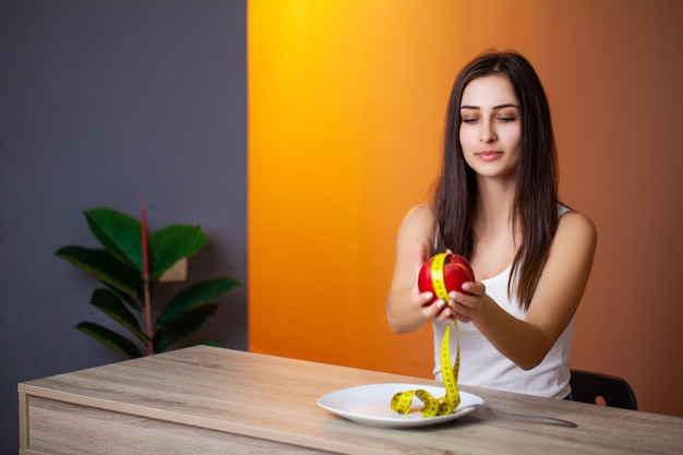 Ritratto di giovane bella donna con il pomodoro e nastro adesivo di misurazione sul piatto