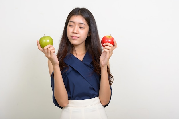 Ritratto di giovane bella donna d'affari asiatica scegliendo tra due mele