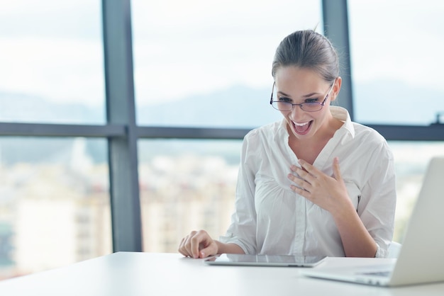 Ritratto di giovane bella donna d'affari lavorare sul computer portatile nell'ufficio moderno e luminoso all'interno