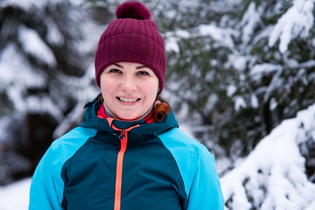 Ritratto di giovane bella donna felice positiva che sorride in una foresta di inverno nevoso