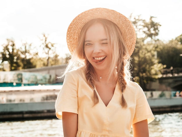 Ritratto di giovane bella donna hipster sorridente in prendisole estive alla moda