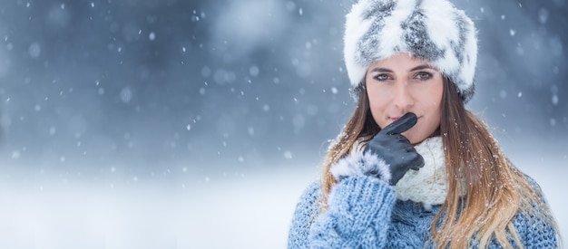 Ritratto di giovane bella donna in abiti invernali e forte nevicata.