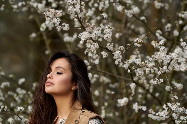 Ritratto di giovane bella donna in alberi in fiore di primavera. alberi a fioritura primaverile.