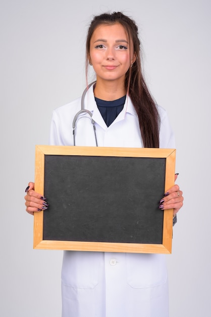 Ritratto di giovane bella donna medico contro il muro bianco