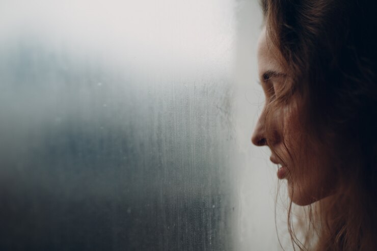 Ritratto di giovane bella donna nel profilo vicino alla finestra appannata