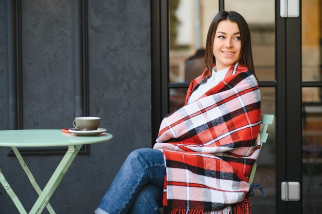 Ritratto di giovane bella donna seduta in un bar all'aperto a bere caffè