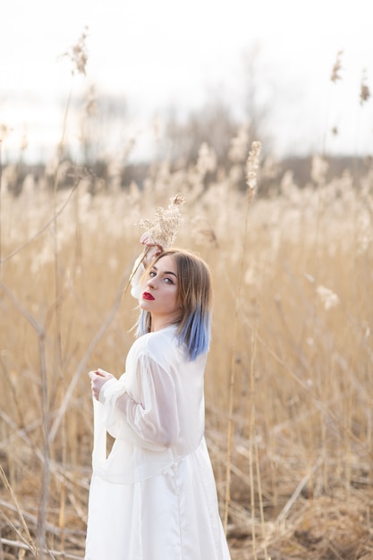 Ritratto di giovane bella ragazza in abito bianco nel campo di grano, a piedi, spensierato.
