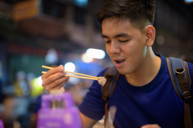 Ritratto di giovane bello turista asiatico uomo esplorando a Chinatown a Bangkok, in Thailandia