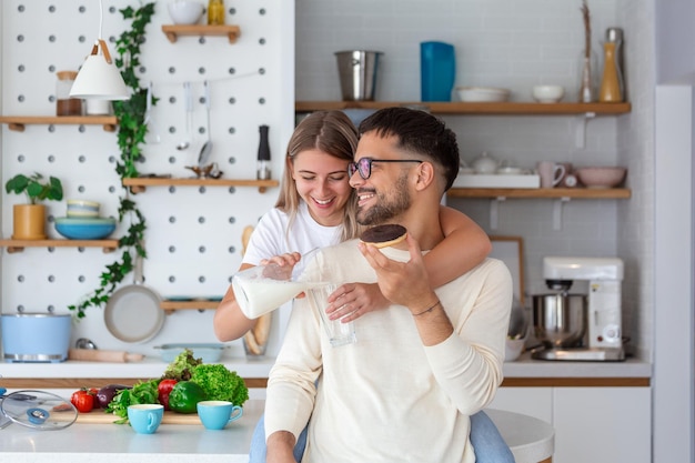 Ritratto di giovane coppia felice cucinare insieme in cucina a casa Cute giovane coppia godendo la colazione insieme lei gli sta versando il latte