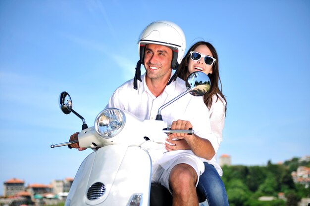 Ritratto di giovane coppia felice di amore su scooter che si diverte in un parco in estate