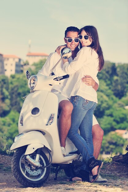 Ritratto di giovane coppia felice di amore su scooter che si diverte in un parco in estate