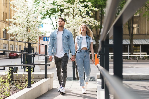 Ritratto di giovane coppia fiduciosa e amorevole che indossa abiti in denim che camminano durante il loro appuntamento in una strada della città