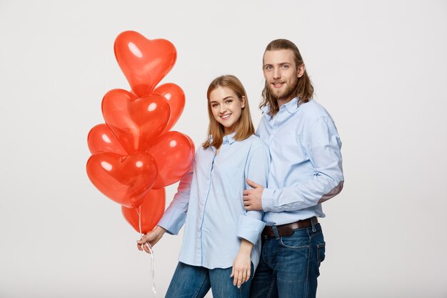Ritratto di giovane coppia indoeuropeo alla moda con palloncini cuore abbracciati a vicenda