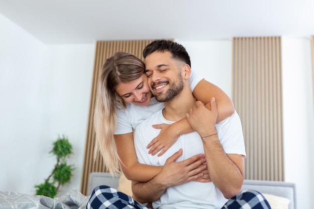 Ritratto di giovane coppia seduta sul letto e guardarsi l'un l'altro Attraente bellissimo nuovo matrimonio uomo e donna in pigiama godersi l'attività mattutina in camera da letto a casa Concetto di relazione familiare