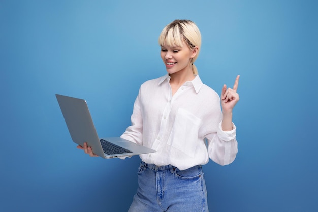 Ritratto di giovane donna abbastanza bionda riuscita di affari in camicetta bianca che lavora facendo uso del computer portatile