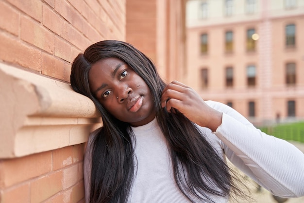 Ritratto di giovane donna afroamericana appoggiata al muro