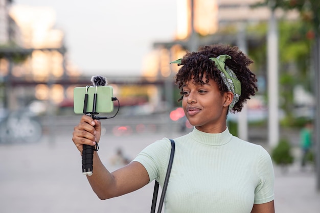 Ritratto di giovane donna afroamericana live streaming mentre si cammina per lo spazio della copia del concetto di giovane blogger della città