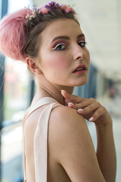 Ritratto di giovane donna alla moda con fiori nei capelli e nel trucco