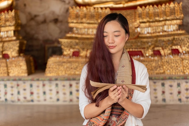 Ritratto di giovane donna asiatica che indossa abiti tradizionali della Thailandia leggendo il sanscrito antico libro Tripitaka del Signore Buddha dhamma