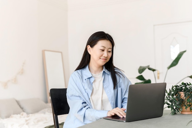 Ritratto di giovane donna asiatica che studia online o che segue un corso web sul computer a casa lavorando sul laptop dall'ufficio a casa Il concetto di formazione a distanza