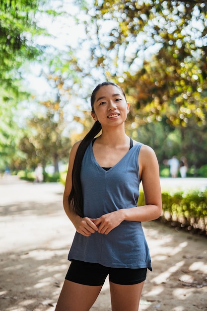 Ritratto di giovane donna asiatica fitness che guarda l'obbiettivo mentre è nel parco