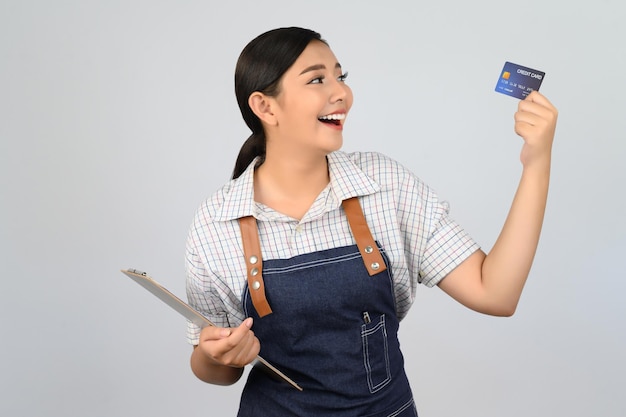 Ritratto di giovane donna asiatica in posa uniforme da cameriera con carta di credito