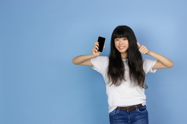 Ritratto di giovane donna asiatica isolata sul fondo blu dello studio