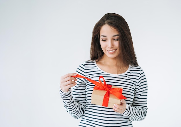 Ritratto di giovane donna asiatica sorridente con confezione regalo in mano su sfondo bianco isolato