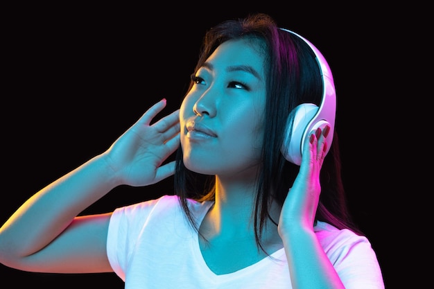 Ritratto di giovane donna asiatica su sfondo scuro per studio al neon Concetto di emozioni umane espressione facciale annuncio di vendita per giovani