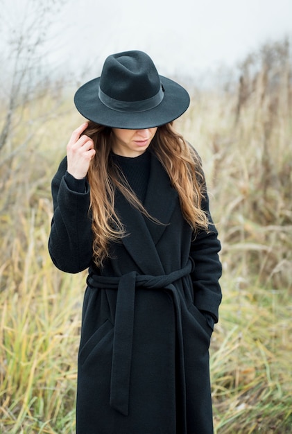 Ritratto di giovane donna attraente in cappotto e cappello neri