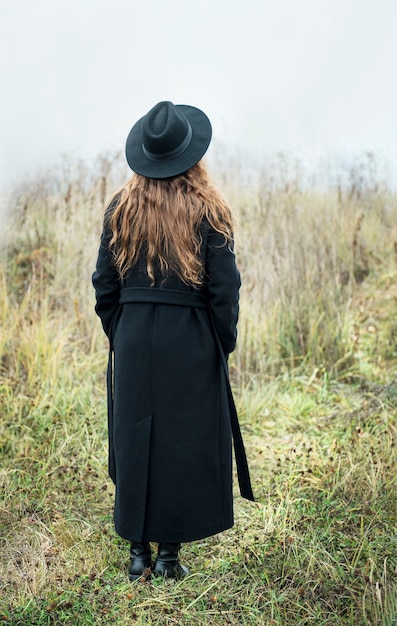 Ritratto di giovane donna attraente in cappotto e cappello neri