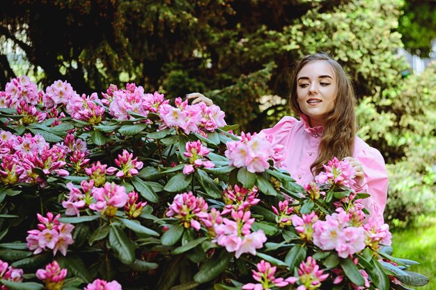 Ritratto di giovane donna attraente in giardino primaverile con un mazzo di lillà. Sfondo primaverile.