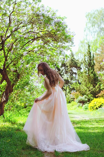 Ritratto di giovane donna attraente nel giardino primaverile con magnolie in fiore. Sfondo primaverile.