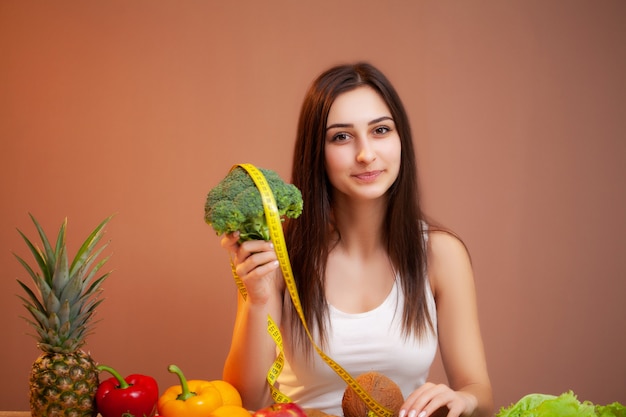 Ritratto di giovane donna bellissima con verdure, frutta e nastro di misurazione