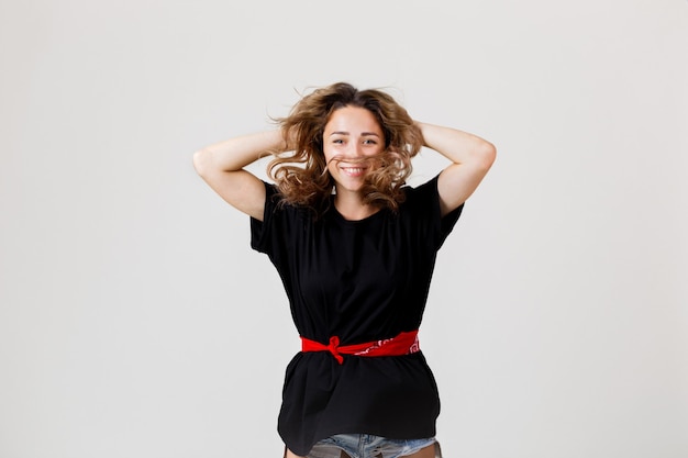 Ritratto di giovane donna bionda allegra che indossa camicia nera e pantaloncini di jeans