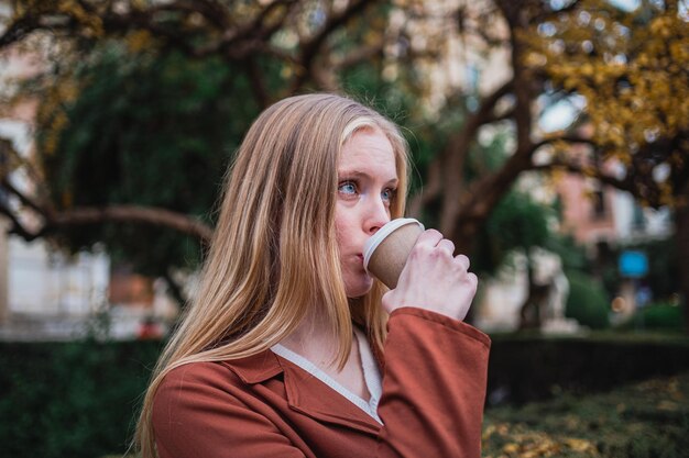 Ritratto di giovane donna bionda che beve una tazza di caffè fuori Lei si sta divertendo