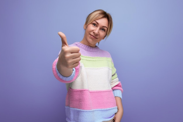 Ritratto di giovane donna bionda sorridente in attrezzatura casual che mostra classe su sfondo viola con copia