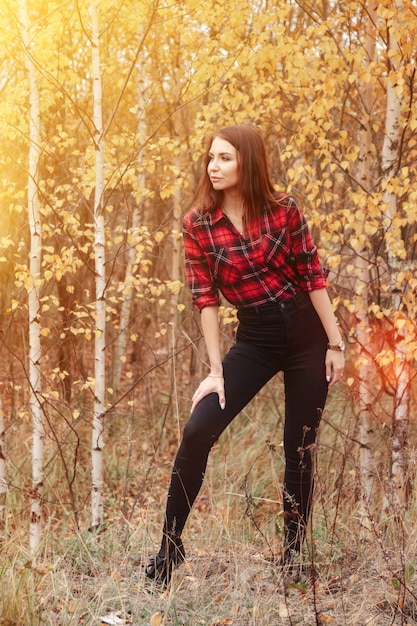 Ritratto di giovane donna carina di aspetto slavo in abbigliamento casual in autunno, in campagna sullo sfondo di un parco autunnale. Bella donna che cammina nella foresta in autunno dorato. Copia spazio