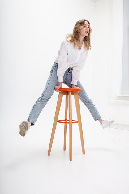 Ritratto di giovane donna caucasica sorridente con capelli lunghi in camicia, jeans, isolato saltando sulle feci. test modello di bella ragazza in abiti di base