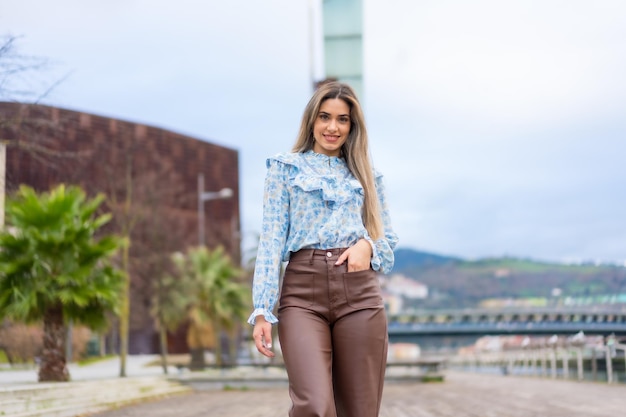 Ritratto di giovane donna che cammina in un parco nel concetto di stile di vita della città camicia blu e pantaloni marroni